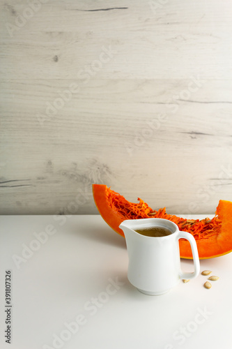 Pumpkin oil in a white sauser and a piece of pumpkin photo
