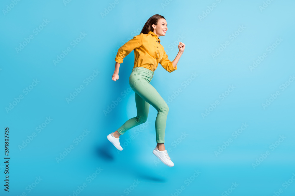 Full size profile photo of cool pretty brunette lady jump wear shirt trousers sneakers isolated on turquoise color background