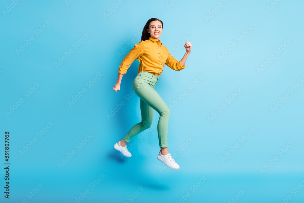 Full size profile photo of cool excited brunette lady jump wear shirt trousers sneakers isolated on teal color background Full size profile photo of cool excited brunette lady jump wear shirt trousers sneakers isolated on teal color background