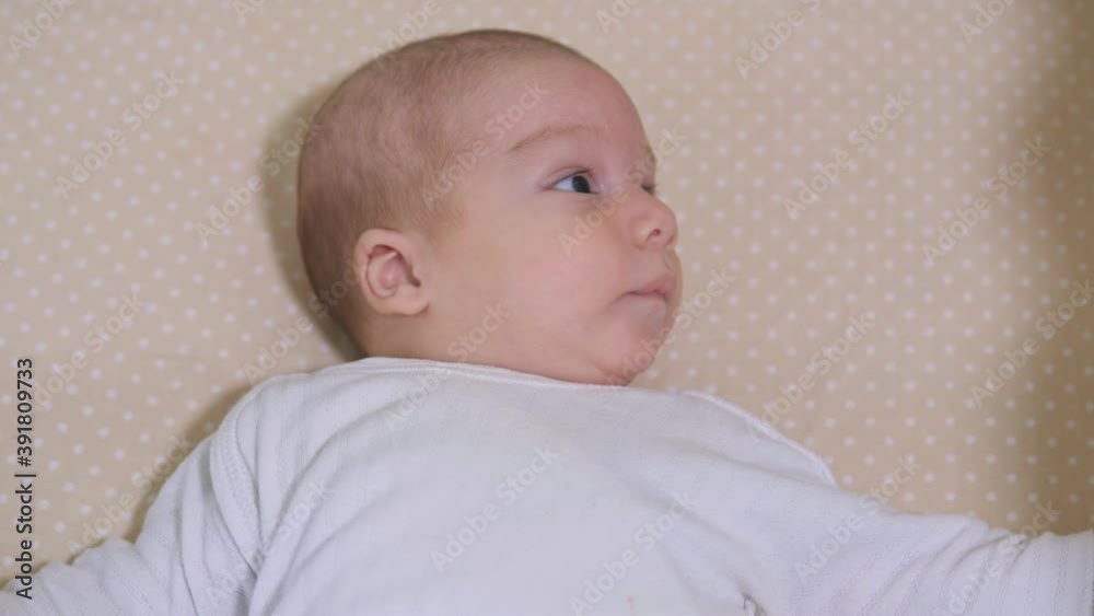 Newborn baby boy lying in bed. Calm cute funny baby wearing pajamas closeup. Naptime Newborn baby boy lying in bed. Calm cute funny baby wearing pajamas closeup. Naptime