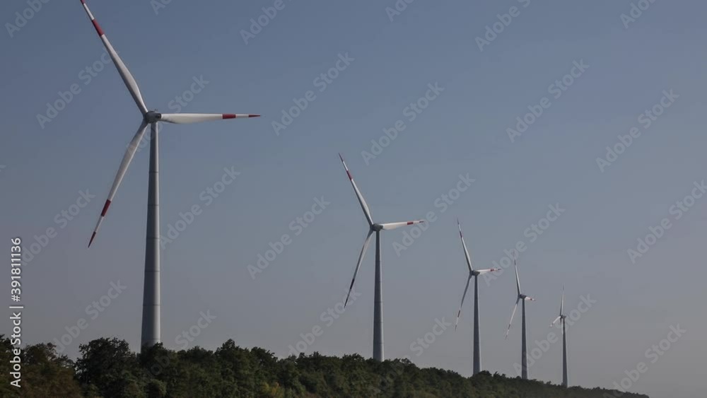 Row of windmills spinning at sunrise against a clear blue sky
Row of windmills spinning at sunrise against a clear blue sky