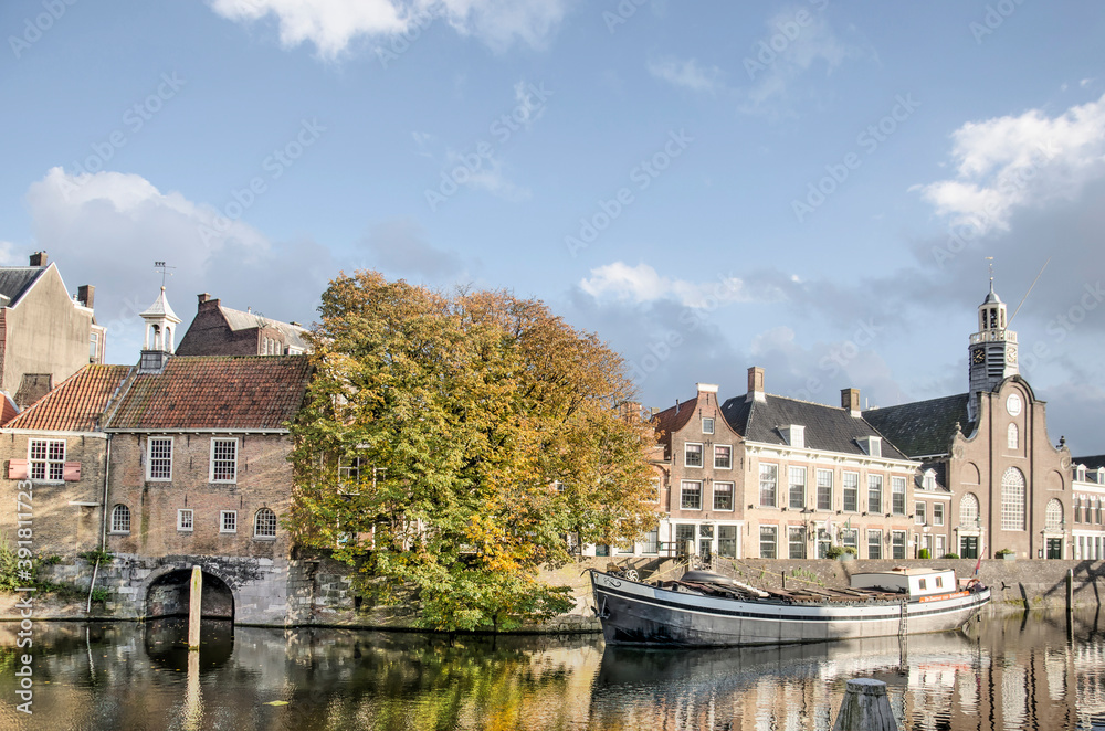 Rotterdam, The Netherlands, October 23, 2020: Aelbrechtskolk canal in Delfshaven neighbourhood with large chestnut tree, historic barge and Pilgrimfathers church