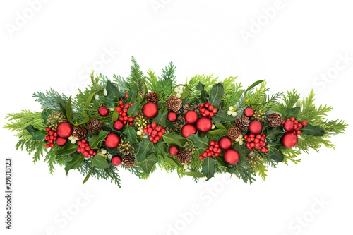 Christmas decoration with red bauble decorations, winter holly with berries, mistletoe, ivy & cedar cypress fir leaves on white background. Decorative display for the festive season. Copy space.