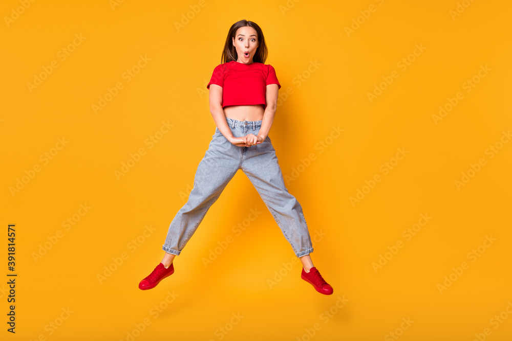 Photo of shocked jumping lady open mouth wear red crop top jeans shoes isolated yellow color background