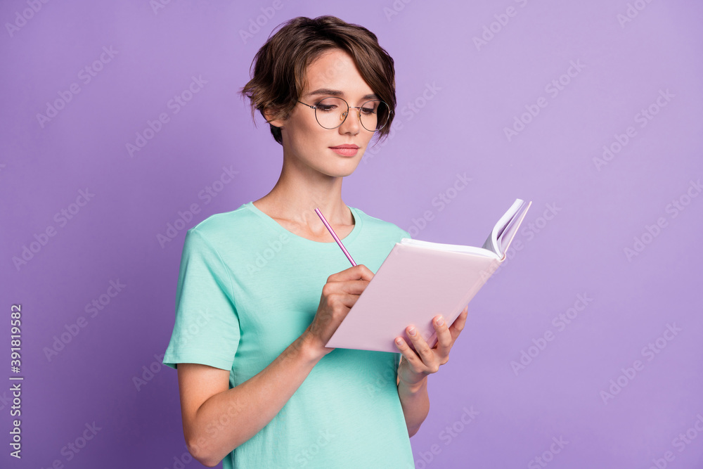 Photo of pretty smart short brown hairdo girl writing diary wear spectacles blue t-shirt isolated on violet color background Photo of pretty smart short brown hairdo girl writing diary wear spectacles blue t-shirt isolated on violet color background