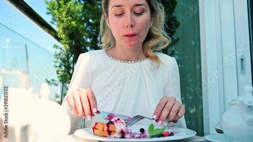 Woman in white dress eating belgian waffles dessert at Nobil restaurant terrace photo