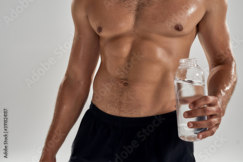 Bodybuilder with shirtless muscular torso holding bottle