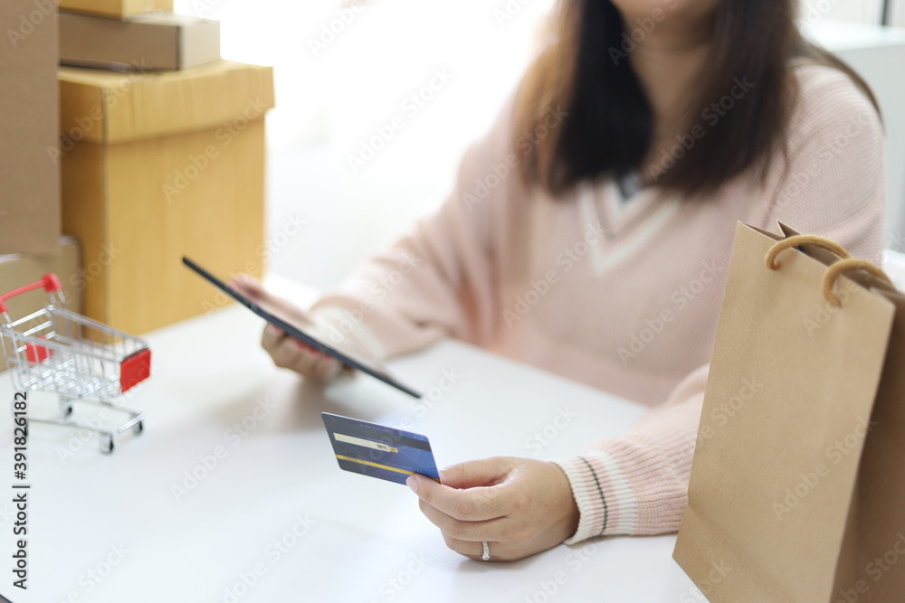 Woman spending money and Small shopping cart with internet banking on Laptop for Internet online e-commerce shopping working from home