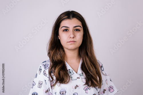 portrait of a white woman dressed as a nurse. She looks seriously at the camera. She wears a colorful and figured coat