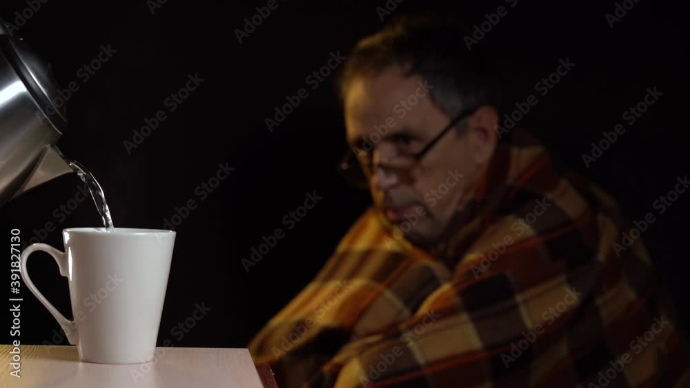 Caring for a sick elderly person. A hot drink for the patient is poured into a white mug. An elderly man blows his nose and waits for a mug of hot drink Caring for a sick elderly person. A hot drink for the patient is poured into a white mug. An elderly man blows his nose and waits for a mug of hot drink