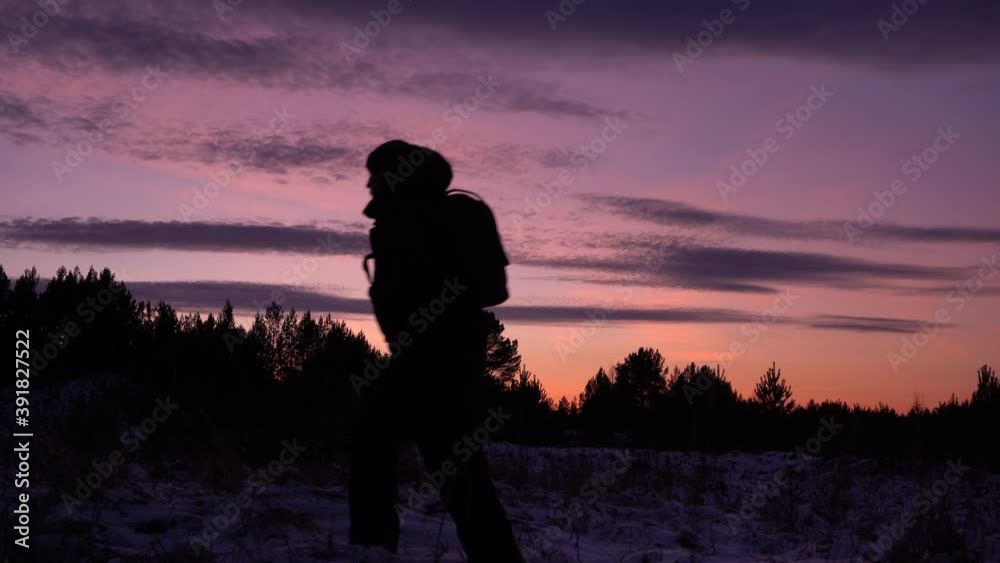 travel concept. black silhouette of a man in a hood against a purple sky. sunset in winter. travel in the winter forest travel concept. black silhouette of a man in a hood against a purple sky. sunset in winter. travel in the winter forest