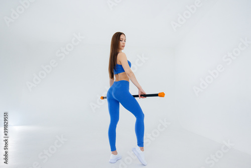 Sexy young girl performs sports exercises on a white background. Fitness, healthy lifestyle