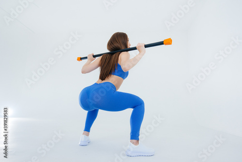Sexy young girl performs sports exercises on a white background. Fitness, healthy lifestyle