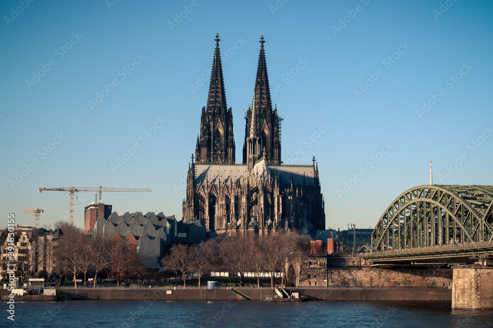 The Hohenzollern bridge over Rhine river on a sunny day. The Cologne Cathedral (Kolner Dom) in the city of Cologne, Germany. It is the largest Gothic church in northern Europe. The Hohenzollern bridge over Rhine river on a sunny day. The Cologne Cathedral (Kolner Dom) in the city of Cologne, Germany. It is the largest Gothic church in northern Europe.