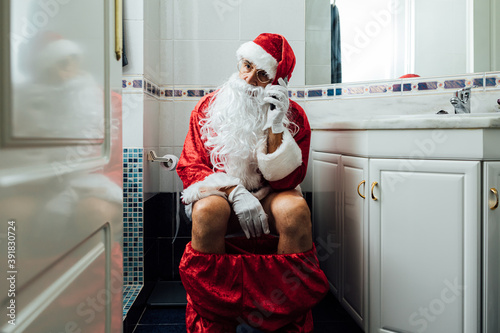 Santa Claus in the bathroom, sitting on the toilet pooping, talking on his mobile