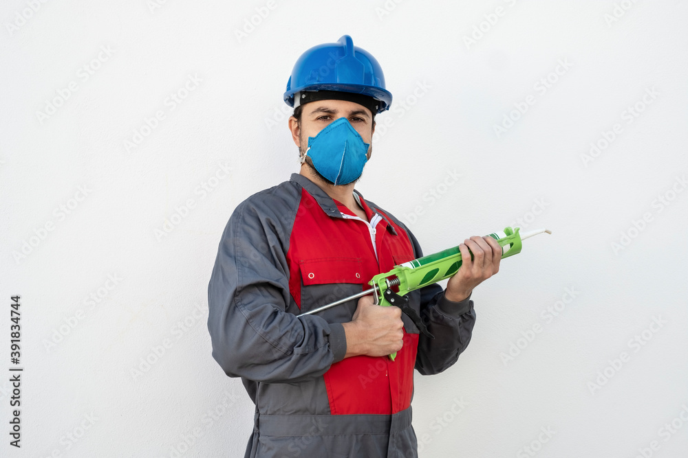 Worker man with silicone gun and protective mask ready to work repairing joints Worker man with silicone gun and protective mask ready to work repairing joints