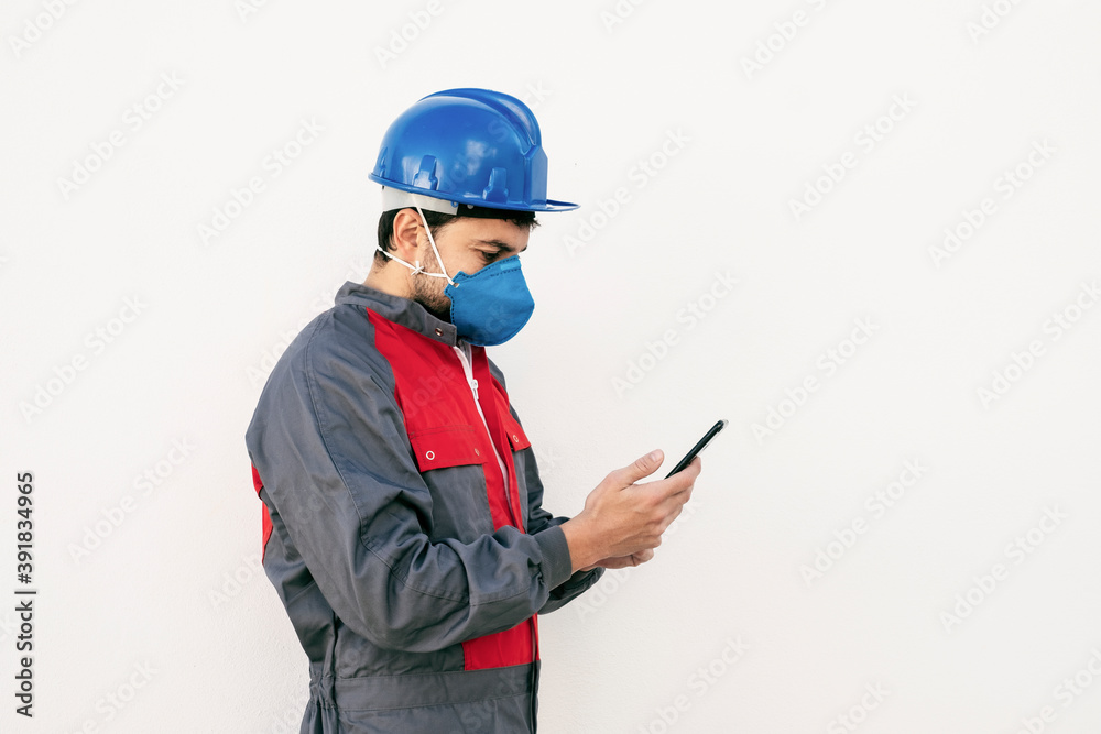 Bearded worker man with face mask looking smart phone