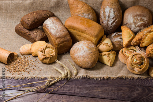 Assortment of bread, ears and grains of wheat on wooden table