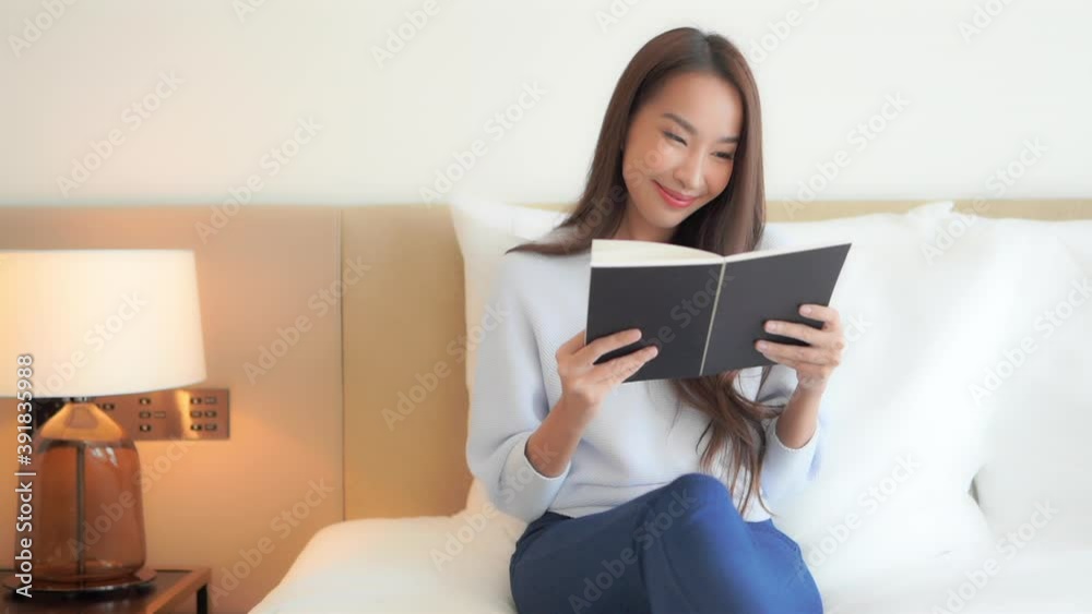 A pretty woman sitting on a bed quietly enjoys reading a book. A pretty woman sitting on a bed quietly enjoys reading a book.