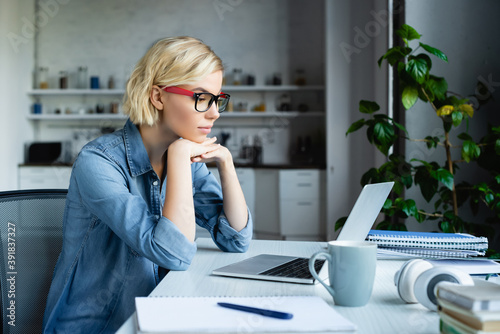young blonde woman in eyeglasses working from home