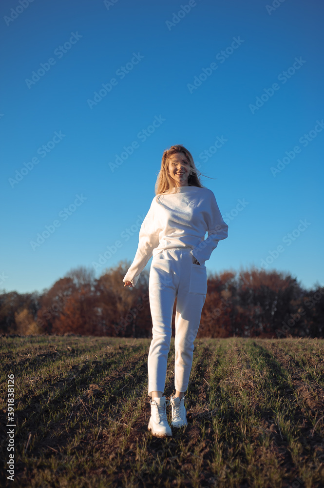 Beautiful fashionable young woman dressed in white sportswear outdoor autumn