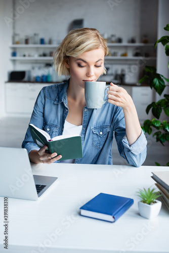 young blonde woman working from home and drinking tea