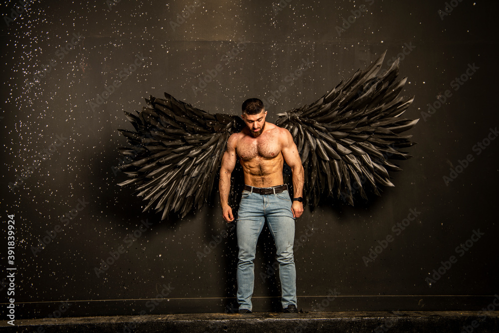 Fotka „handsome physically well-developed man with black angel wings on a  dark background“ ze služby Stock | Adobe Stock