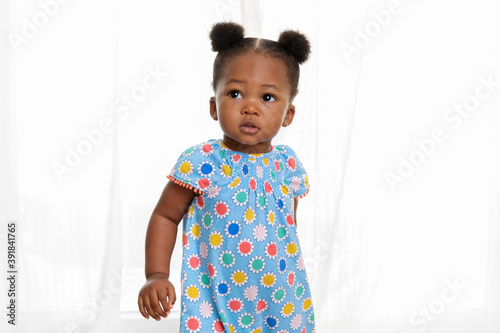 Portrait of toddler girl with hair buns in front of curtains photo