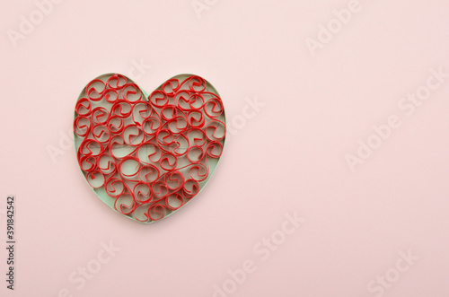 A red origami heart on pink background