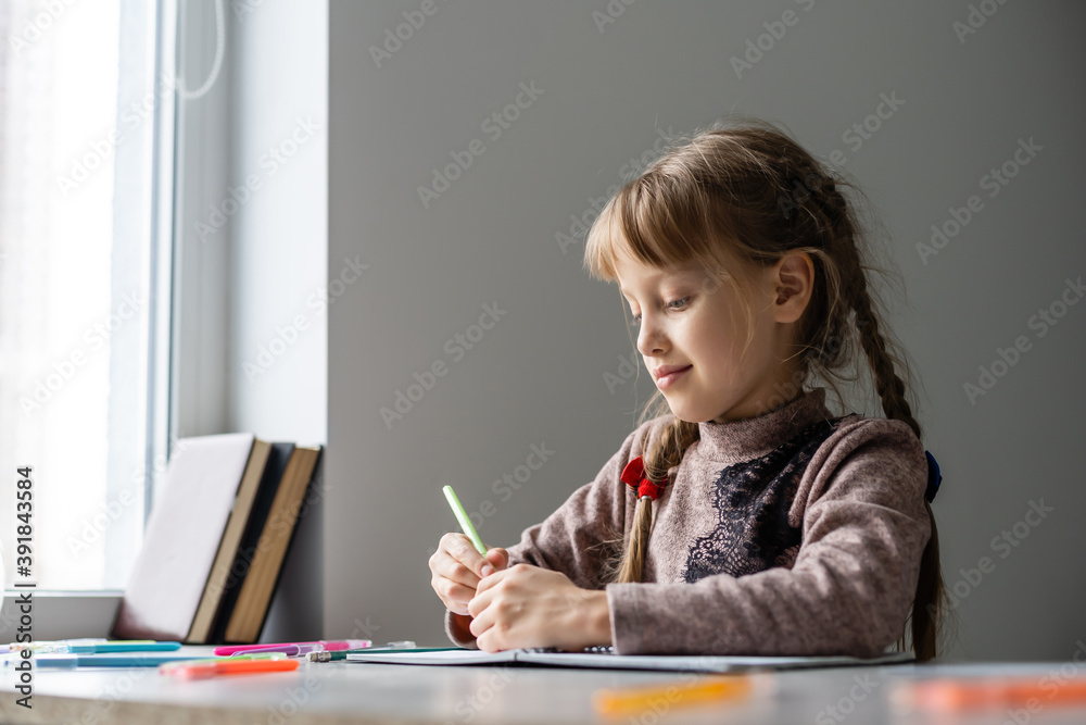 Cute little girl doing her homework, close-up, on home interior background Cute little girl doing her homework, close-up, on home interior background