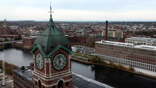 Ayer Mill Clock Tower In Lawrence, Massachusetts Overlooking Merrimack River And Bridge At Daytime - aerial close up, orbiting shot