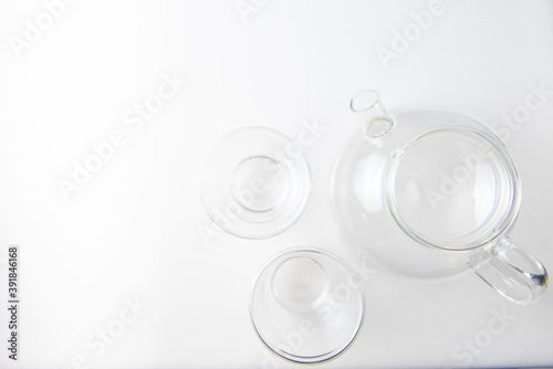 set of glassware transparent teapot and two mugs on white background