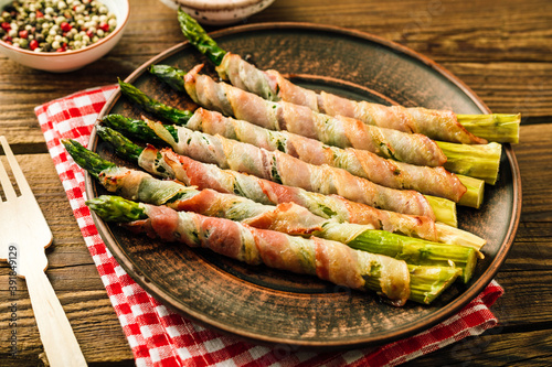 Asparagus shoots baked in bacon. Snack on wooden background
