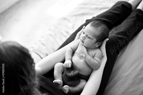 Young Mother Holding Newborn Baby in Bed at Home