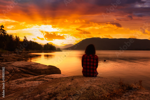 Girl Watching a Peaceful Sunrise on the Ocean Coast. Located in Saltery Bay, Sunshine Coast, British Columbia, Canada. Dramatic Colorful Sky Art Render