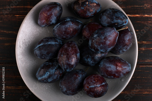 Fresh appetizing plums in a gray bowl, summer concept, copy space.