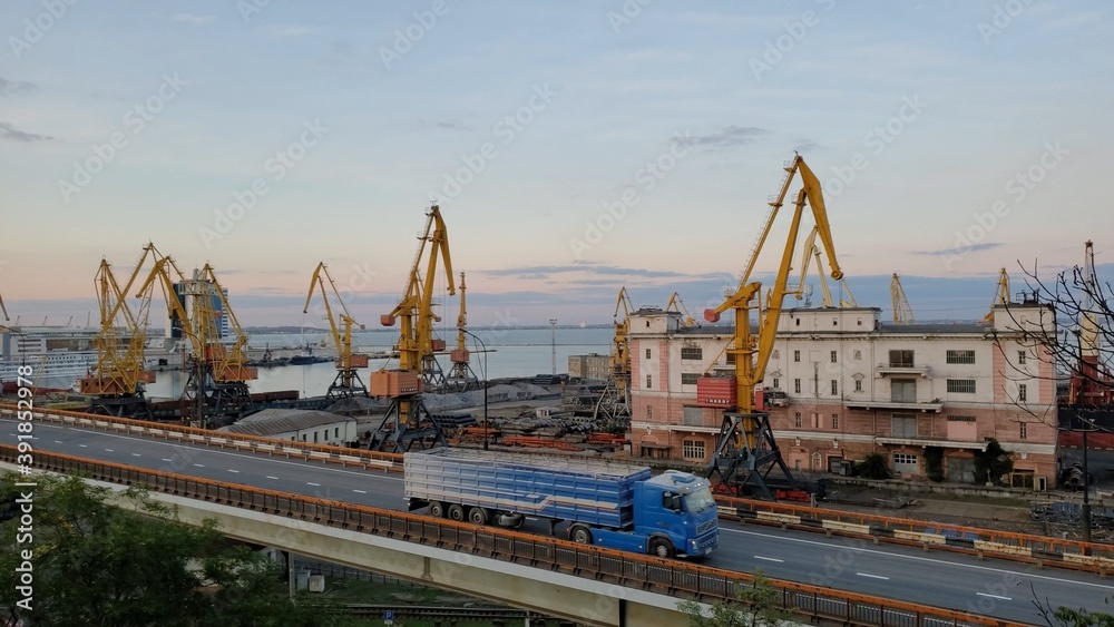 Industrial port landscape with cargo cranes and cargo vehicle traffic by overpass