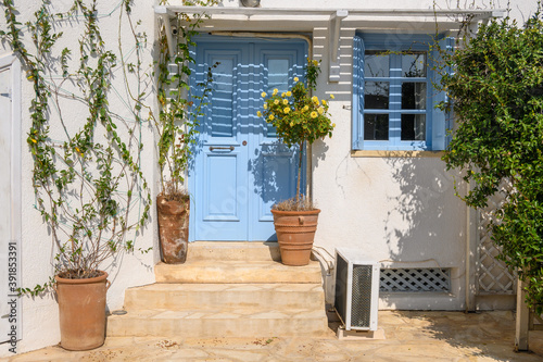 Entrance gate to typical Greek style apartments decorated with flower pots on street in Chora town on Folegandros Island. Cyclades, Greece © vivoo