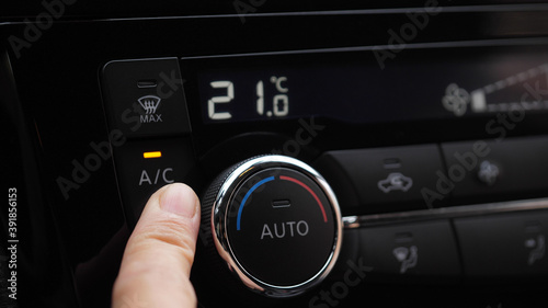 set up air conditioner in the car. Hand turns air conditioner ring. Display indicates temperature inside the car. Cooling air in the car