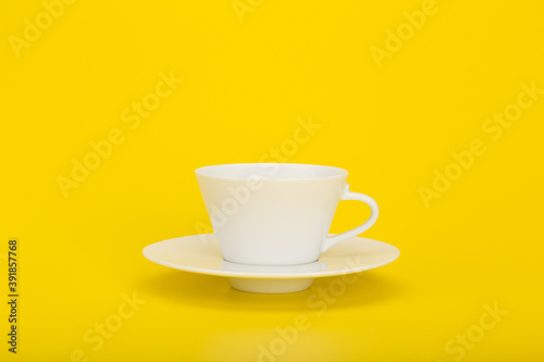 Minimalistic still life with cup of coffee on yellow background