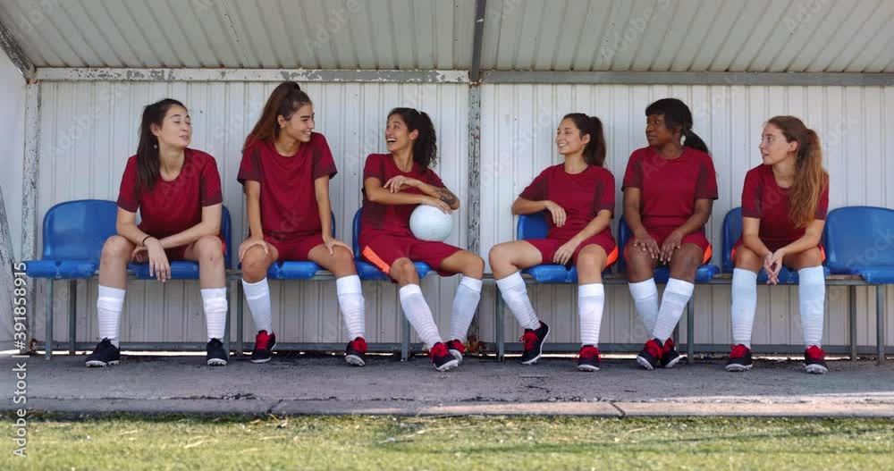 Group of teenagers sitting on bench talking after soccer practice
