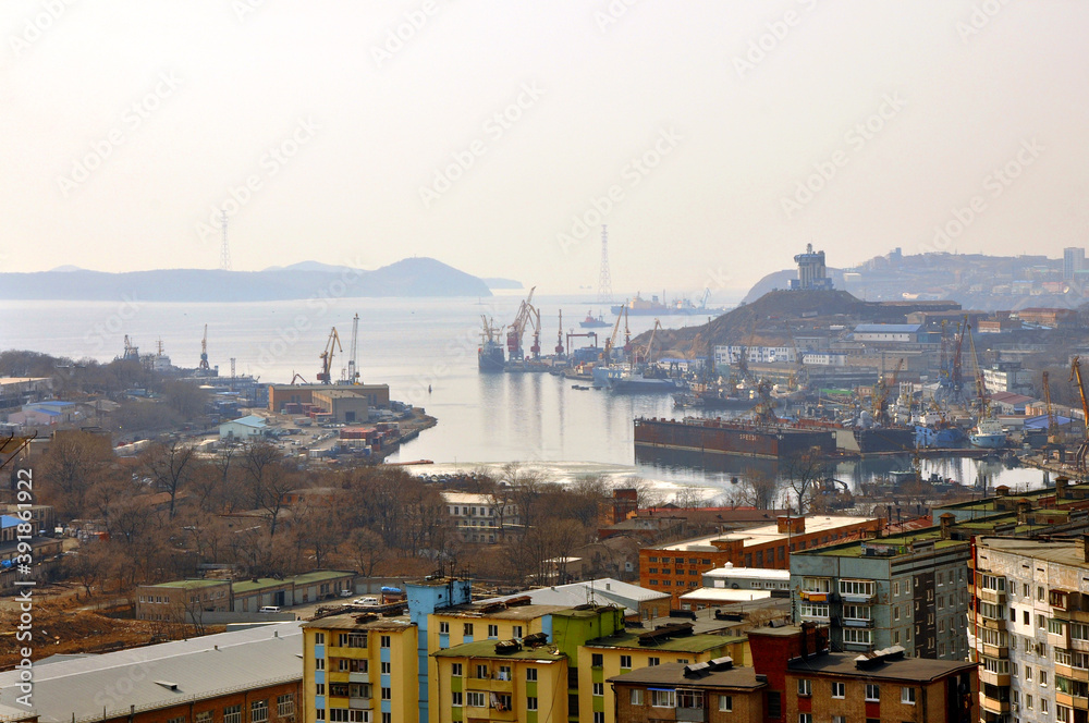 Panoramic top view of Vladivostok city in haze: residential buildings, harbour, ships, Japanese sea bay and hills in the background. Primorsky Krai, Russia.