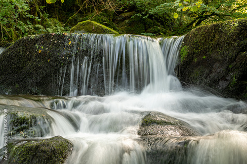 Long exposure of a waterfall on the Hoar Oak Water river flowing through the woods at Watersmeet in Exmoor National Park photo