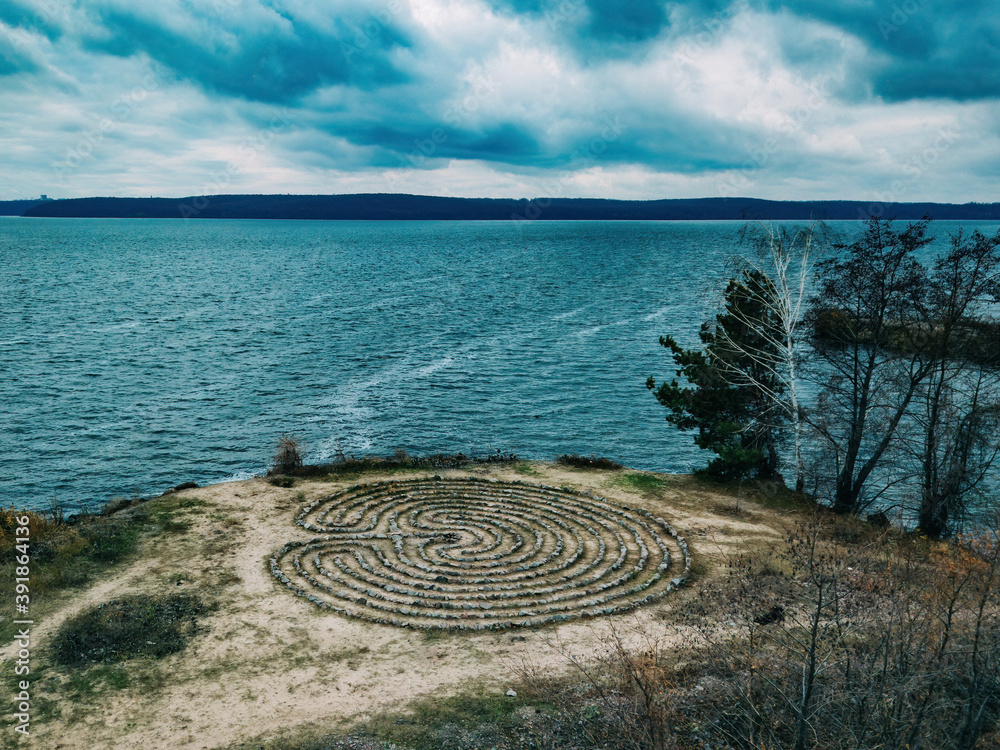 Spiral labyrinth made of stones on the coast, aerial view Spiral labyrinth made of stones on the coast, aerial view