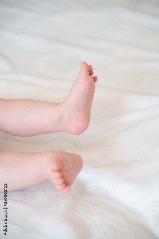 tiny, cute, bare feet of a little caucasian baby girl or boy on a white soft and cosy background, with pink skin, playfully wriggling its toes in excitement tiny, cute, bare feet of a little caucasian baby girl or boy on a white soft and cosy background, with pink skin, playfully wriggling its toes in excitement