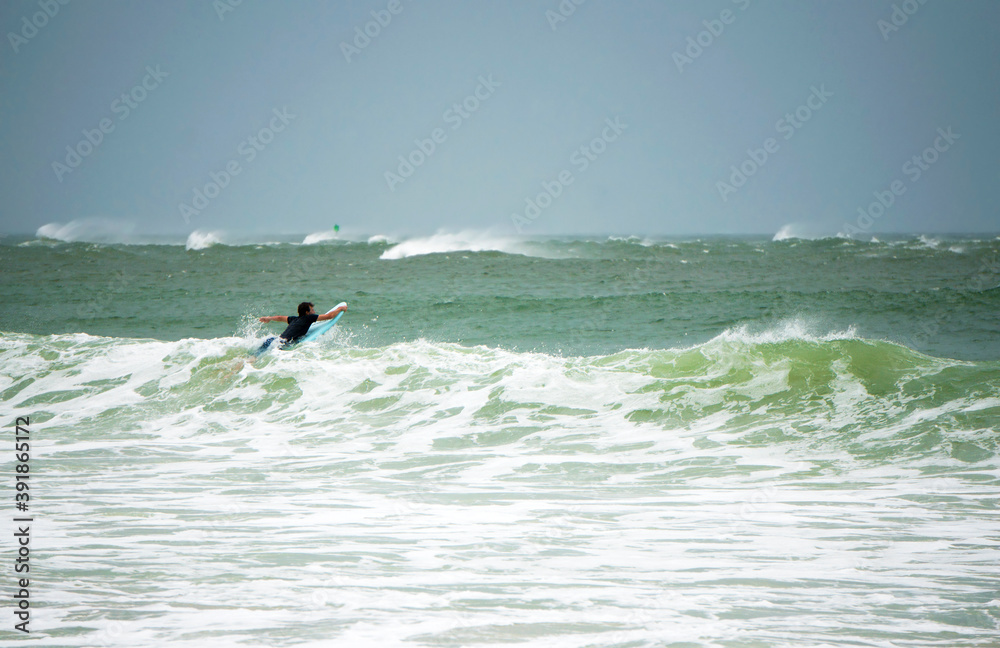 A surfer braves the high surf during tropical storm ETA on St. Pete Beach, Florida A surfer braves the high surf during tropical storm ETA on St. Pete Beach, Florida