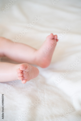 tiny, cute, bare feet of a little caucasian baby girl or boy on a white soft and cosy background, with pink skin, playfully wriggling its toes in excitement 