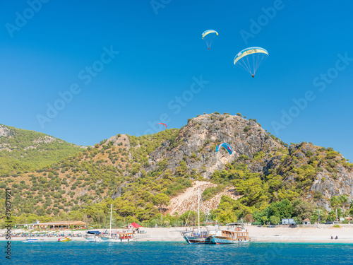 paraglide in blue sky above sand beach and yacht with copy space