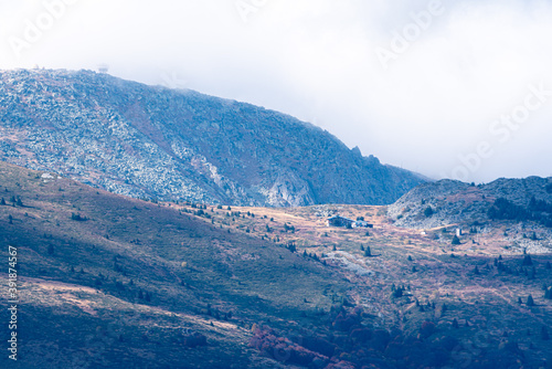 Misty blue cold mountain lodge rocky hillside high scarce sunrays cloudy moody day © Valentin