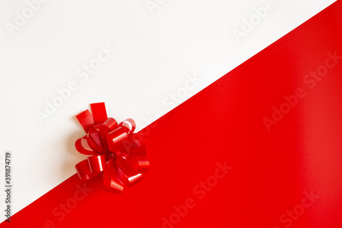 Red plastic bow on a red and white diagonal paper texture
